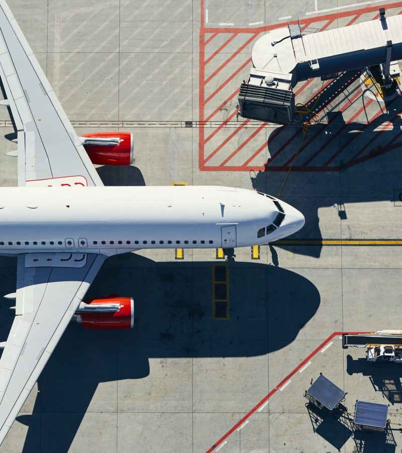 Aerial view of airport. Airplane is taxiing to gate of terminal.