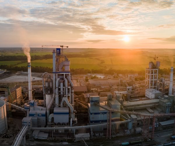 Aerial view of cement factory tower with high concrete plant structure at industrial production area. Manufacturing and global industry concept.